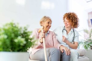 Older LGBTQ+ couple speaking with a compassionate assisted living staff member in a bright common room.